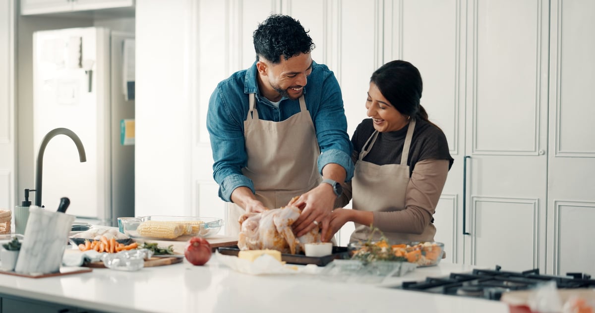 A happy couple preparing a chicken dinner together in their home kitchen